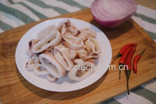 展示正在锅中焯水的鱿鱼圈,旁边有姜片和料酒 冰冻鱿鱼圈焯水过程