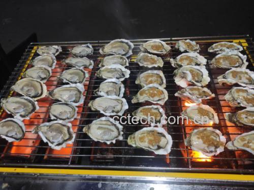 厨房中厨师正在用炭火烤制新鲜生蚝,展现料理过程的美感 生蚝烹饪场景