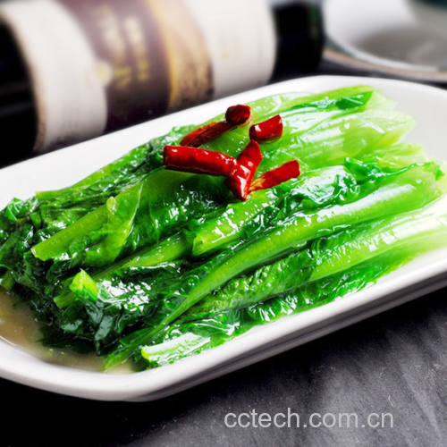 一口黑色铁锅中正在大火翻炒油麦菜与洋葱,菜叶翻滚呈翠绿色,洋葱条半透明状,锅中有轻微油烟升腾,显示高温快炒场景 油麦菜与洋葱正在翻炒过程