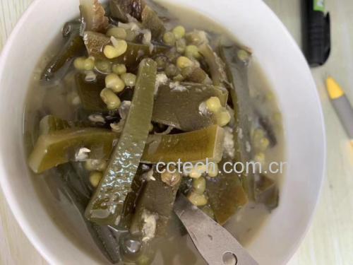 厨房操作台上的炖锅正在慢火炖煮海带骨头绿豆汤,旁边摆放着洗净的海带、猪骨和绿豆 海带骨头绿豆汤制作过程图