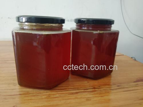 温馨的家庭厨房场景,一瓶蜂蜜和几个玻璃杯摆放在木质餐桌上 家庭厨房桌上摆放蜂蜜与玻璃杯