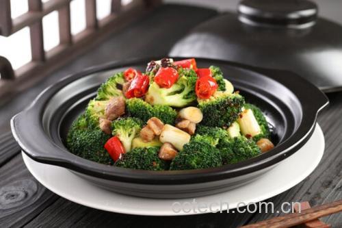一位厨师在明亮的家庭厨房中使用铁锅翻炒西兰花与香菇,锅中食材色泽鲜亮,伴有少量蒜片和酱油调味,蒸汽升腾,体现健康中式烹饪过程 家庭厨房中正在翻炒西兰花与香菇的锅具场景