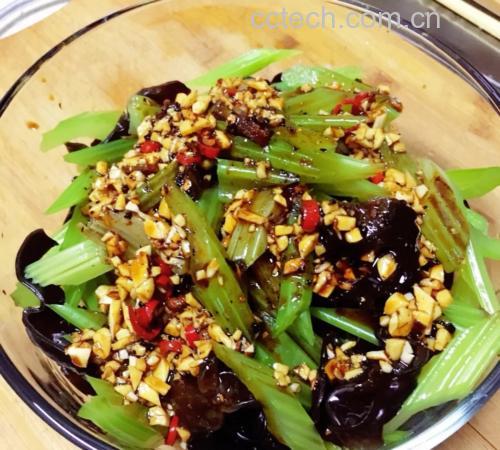 一道色彩鲜艳的凉拌菜摆放在白色瓷盘中,主要食材为翠绿色的山芹段、黑色的泡发木耳和红色细椒丝,表面淋有油光,撒有蒜末,旁边点缀柠檬片和香草叶 蒜蓉山芹拌木耳成品图