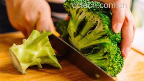 西兰花预处理特写：去皮后的嫩绿茎部与带十字切痕的斜片，旁边摆放完整西兰花与削皮刀