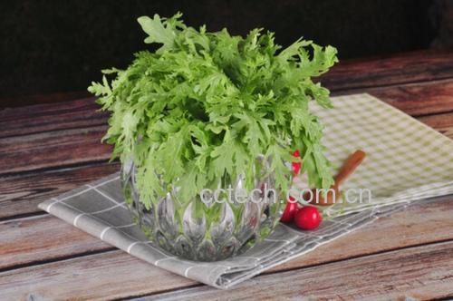 特写镜头:新鲜焯过水的翠绿菠菜整齐码放在白瓷盘中,表面微润无水渍;右侧放置透明玻璃瓶装琥珀色米醋,瓶身标签清晰可见 菠菜焯水后沥干装盘,旁边摆放玻璃瓶装米醋与小勺,桌面铺浅灰麻布,自然光拍摄