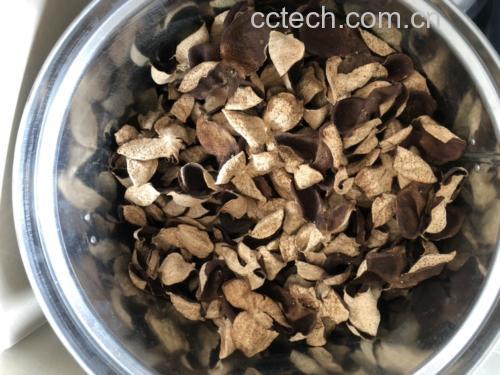 高清微距摄影:左侧为三年新会陈皮切片(表皮棕褐、内囊雪白、油室饱满),右侧为大红袍花椒颗粒(紫红带麻点、表面具蜡质光泽),中间玻璃壶中为淡琥珀色药汤,汤面浮有细密油珠,背景为木质砧板与青瓷碗 陈皮与花椒配伍煮水特写