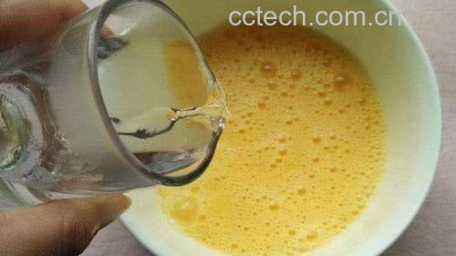 厨师正在白色瓷碗中用力搅打鸡蛋液,蛋液泛起细腻泡沫,旁边放有盐罐、胡椒瓶和量勺,展示标准化调味过程 图片描述