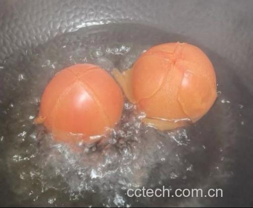 一位厨师正在将新鲜红润的西红柿放入清水中清洗,旁边放置一碗淡盐水,另一只手正用刀在西红柿顶部划十字,准备进行热水烫皮处理 西红柿清洗与去皮过程