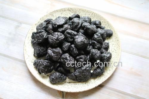 新鲜炮制的熟地黄切片呈乌黑色、油润有光泽,旁边摆放着饱满圆润的黑色种皮大豆,两者置于陶碗中,背景为传统中药柜,体现食材道地性与药食同源理念 熟地黄与黑豆原材料特写