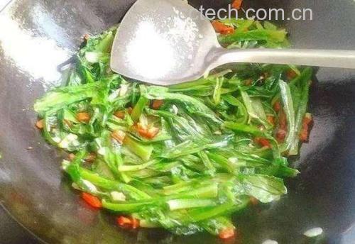家庭厨房中正在翻炒红菜苔的场景