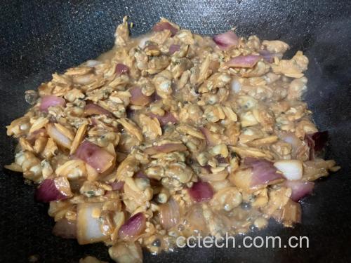 厨房灶台上正在翻炒花蛤的铁锅,火焰升腾,花蛤已微微开口,辅料包括青红椒丝、蒜片、葱段,旁边摆放切好的调料,整体呈现中式家常烹饪氛围 家庭烹饪花蛤场景