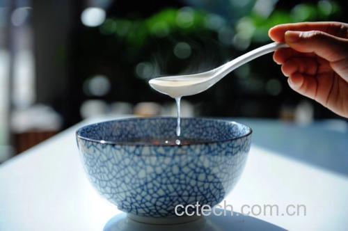 一杯冲泡好的黑玛卡粉饮品,旁边放着勺子和干制的黑玛卡块根 黑玛卡粉冲泡图