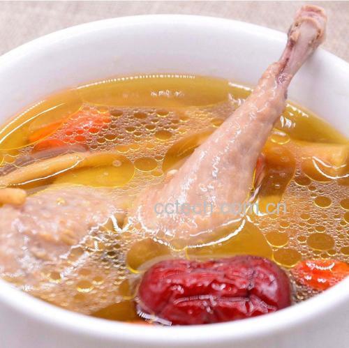一碗热气腾腾的鹿鞭炖鸡汤,汤色金黄清澈,可见数片鹿鞭横卧其中,周围配有红枣、枸杞、姜片等辅料,碗旁放置木勺,背景为中式厨房环境,体现家庭养生烹饪场景 鹿鞭炖汤成品图