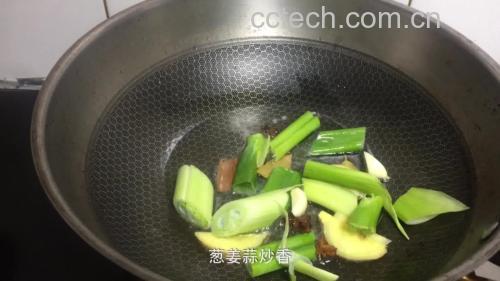 一口黑色铁锅正置于燃气灶上,锅中翻炒着翠绿的无筋豆,大蒜片清晰可见,蒸汽升腾,厨师手持锅铲正在进行颠勺动作 无筋豆在炒锅中翻炒的过程