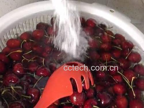 一位厨师正在用白色纱布过滤锅中的桃形李果浆,深粉色果汁缓缓流入下方玻璃容器中,背景为木质料理台和不锈钢厨具,强调手工制作的洁净与专业感 桃形李果汁过滤过程