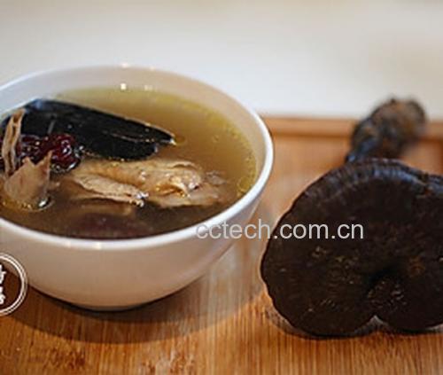 一碗盛满的灵芝煲鸡汤特写,汤色呈琥珀金色,表面有细小油珠,碗中可见灵芝薄片、红枣、枸杞和鸡块,背景虚化,营造出温暖养生的氛围 成品汤品图