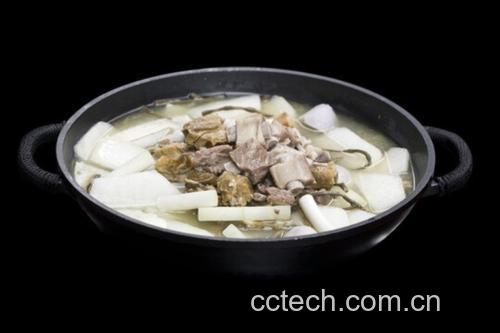 一个白色陶瓷砂锅置于木质灶台上,锅盖微启,热气袅袅升起,锅内可见乳白色的汤汁正在微微翻滚,清晰可见炖煮中的雷竹笋块与猪骨,旁边摆放着生姜片和调料碗,展现家庭厨房温馨炖汤场景 雷笋炖汤炖煮过程图