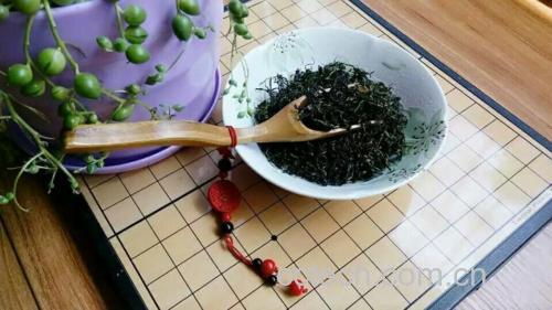 全景拍摄:阳光洒落的窗边茶桌上摆放着一套完整的茶具组合,包括白瓷盖碗、玻璃公道杯、三个小瓷杯,一位女士正端起茶杯轻啜,背景虚化可见绿植与书架,整体氛围宁静雅致 品茶场景