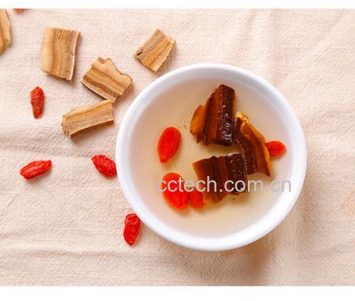 一口砂锅正在小火慢炖灵芝片和枸杞,锅内液体呈淡琥珀色,旁边摆放着干燥的灵芝切片和红色枸杞,背景为木质厨房台面,体现自然养生氛围 灵芝枸杞养生茶熬煮过程