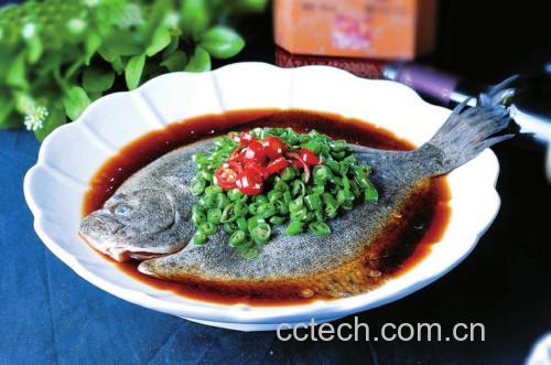 一道完成的剁椒多宝鱼摆放在白色瓷盘中,鱼身铺满红亮剁椒和金黄蒜粒,表面淋有热油光泽,点缀翠绿葱丝和红色辣椒丝,背景为木质餐桌与米饭碗,整体呈现诱人的家常宴席氛围 成品展示图
