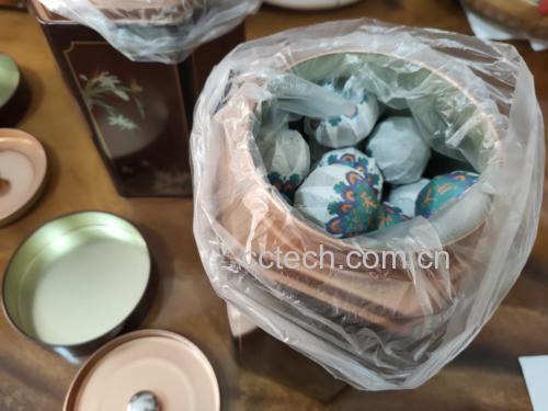 柚子普洱茶成品展示,茶包与散茶并列,背景为自然茶山与果园 柚子普洱茶成品展示图