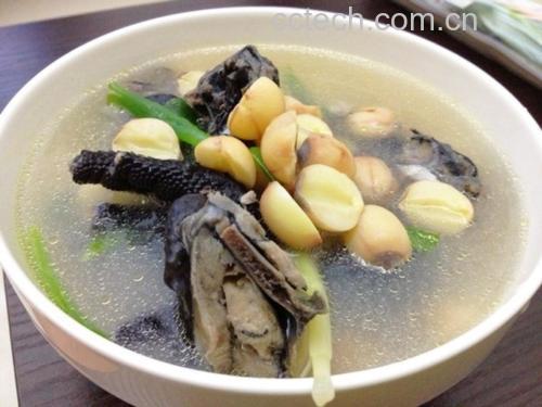 砂锅慢炖的莲子老母鸡汤,汤色乳白微黄,表面浮有少量金黄色鸡油,可见完整去芯莲子与鸡块交错分布,热气升腾,配以青葱点缀,展现家庭烹饪的真实场景 莲子炖老母鸡汤成品图