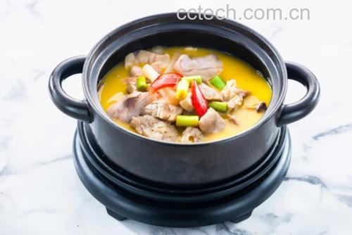 深色砂锅中翻滚着棕红色的炖肉汤汁,厨师正用手夹着几片山楂干轻轻放入锅中,蒸汽升腾,周围散落着姜片和香料,展现关键添加环节 炖肉过程中加入山楂干的特写镜头