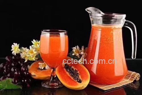 慢速螺旋榨汁机正在工作,透明料斗中可见橙黄色细腻果汁缓缓流入玻璃量杯,杯壁凝结细密水珠,量杯刻度显示180ml,旁置不锈钢勺舀起少量果汁展示其均匀无分层状态