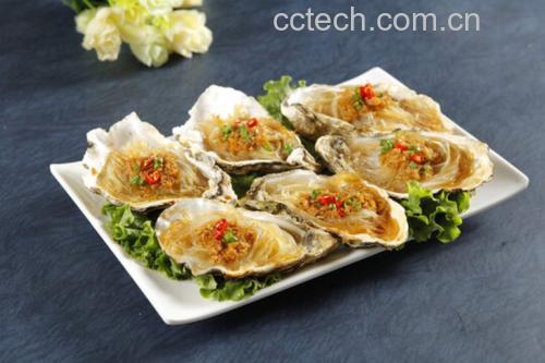 厨师手持夹子将65℃预熟的生蚝肉轻放在铺满粉丝的蒸盘上，旁边备好金黄蒜蓉酱和香菜末