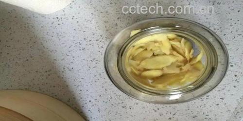 透明玻璃罐中盛满晶莹剔透的泡姜片，液体清澈，姜片呈浅琥珀色，旁边摆放着一双竹筷