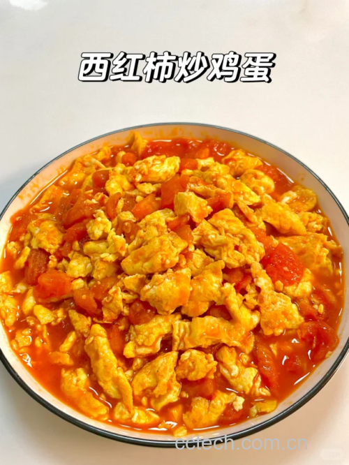 锅中正在翻炒的西红柿与鸡蛋混合物,红汁四溢,蛋块蓬松金黄,热气腾腾