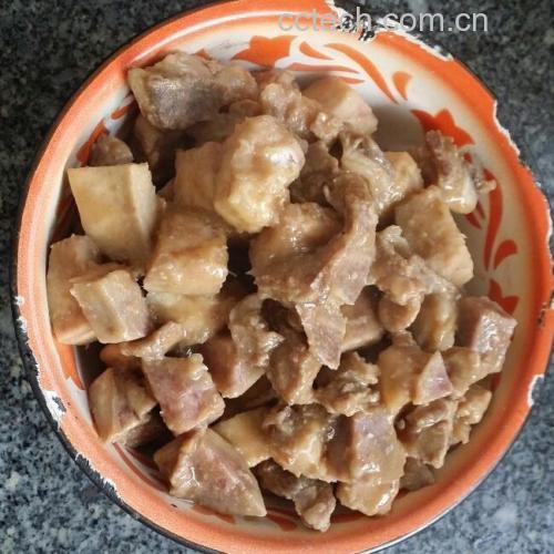 成品芋头炖肉盛于白瓷碗中，肉块酥烂，芋头完整，汤汁油亮，旁边配有米饭和绿叶菜