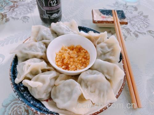 一家人围坐在餐桌前吃热气腾腾的豆角肉饺子，桌上摆着醋碟和蒜泥，氛围温馨