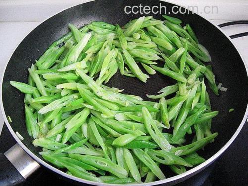 厨房中正在清炒软青豌豆的场景