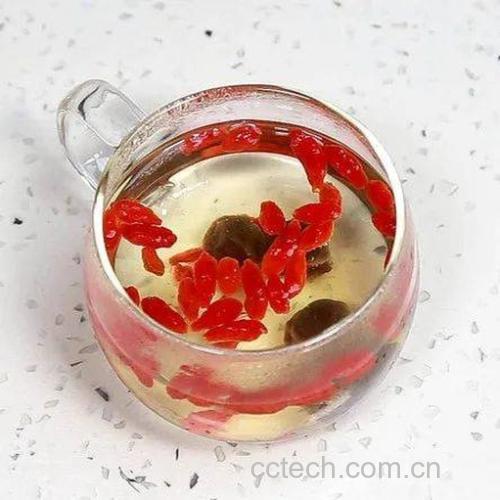 玻璃罐中盛放着刚煮好的红枣枸杞茶，液体呈琥珀色，几片红枣漂浮其中，旁边摆放木质茶匙
