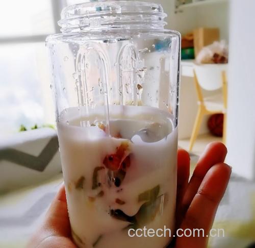 一杯盛满乳白色奶昔的玻璃杯，旁边放着半根香蕉和一小碟切好的海参丁