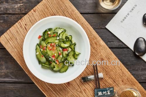 一张木质餐桌上展示三种不同风格的黄瓜西红柿料理:传统凉拌、西式酸奶沙拉、中式热炝版本,配有餐具和柠檬片装饰