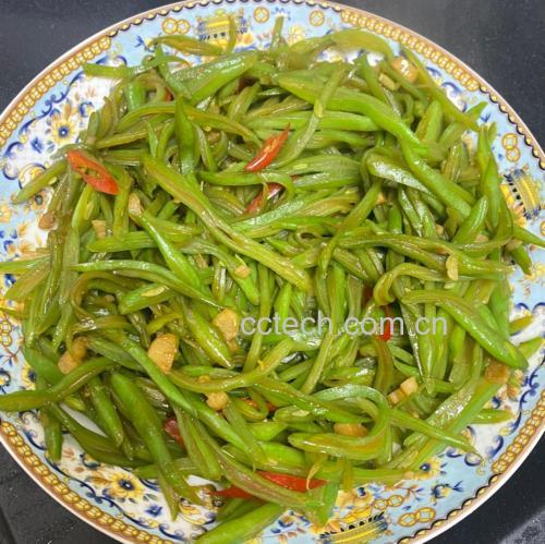 一盘刚出锅的清炒四季豆莴笋丝，菜肴呈翠绿与乳白相间，表面有轻微油光，盛放在白色瓷盘中，背景虚化为家庭餐桌环境