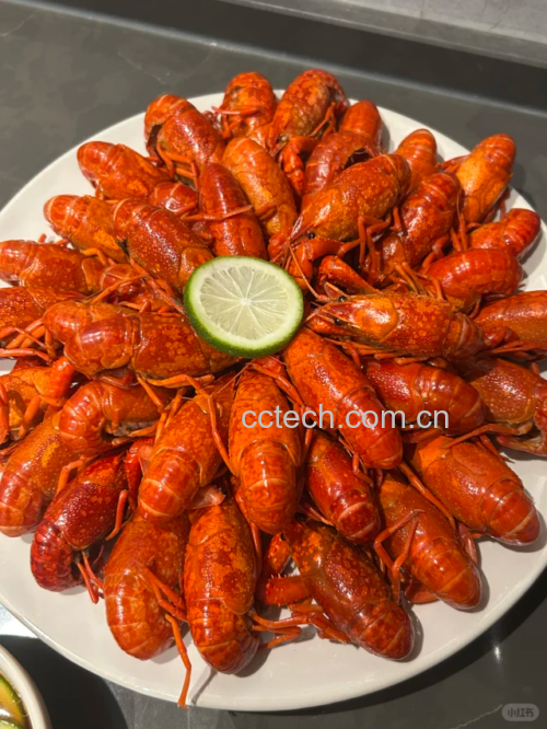 不锈钢蒸锅内正在蒸制小龙虾,蒸汽翻腾,虾体已变为鲜艳红色,整齐排列于竹制蒸屉上