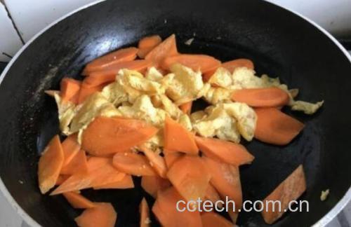 锅中正在翻炒胡萝卜与蘑菇,食材呈金黄色,表面微焦,蒸汽升腾,厨师手持锅铲操作