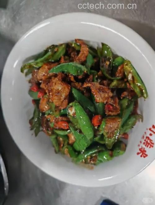 一盘以青小米椒为主料制作的湘菜小炒肉，青红小米椒切圈与瘦肉片同炒，色泽鲜艳，油光发亮