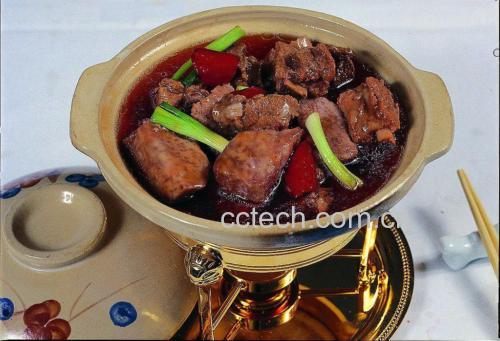家庭厨房中用砂锅炖煮白条羊肉的场景