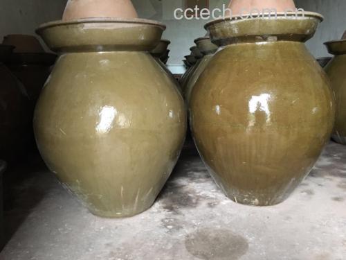 透明玻璃泡菜坛中整齐码放的红色辣椒与白色蒜片，清澈盐水完全覆盖食材，旁边摆放空碗与漏勺
