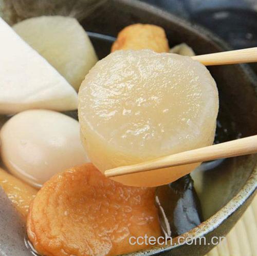 成品关东煮萝卜盛于白色瓷碗中，配以竹筷和柠檬片装饰，背景虚化突出主体