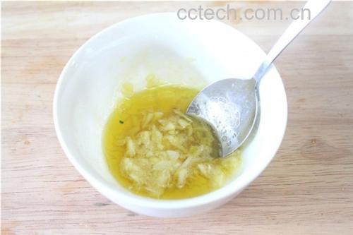 一盘刚出锅的意式蒜香橄榄油拌面,面条裹满金黄色蒜油汁,表面点缀焦香蒜片与红色辣椒碎,旁边放着一只木柄蒜杵和空石臼,体现从原料到成菜的全过程