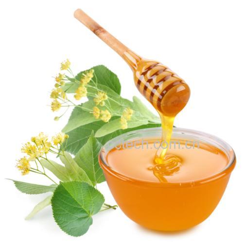 玻璃勺舀取流动的浅琥珀色椴树蜂蜜特写