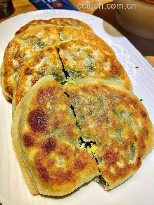 刚出锅的韭菜盒子特写,表面金黄酥脆,切开后露出翠绿馅料